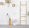 A bathroom scene with a toilet, toilet paper holder, and decorative items. Anteprima dell’immagine prodotto