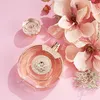 A bottle of Guess Bella Vita Rosa perfume is displayed on a pink background with decorative flowers. Voir les images du produit