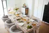A dining table set for a meal with plates, food, and chairs. Náhľad obrázku produktu