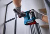 A person wearing gloves is using a cordless hammer drill to drill into a metal frame. Produktbild-Vorschau