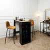 A bar area with a high table and two bar stools, set up in a room with decorative wall molding and a floor lamp. Voir les images du produit