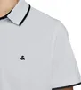 Close-up of a person wearing a light gray polo shirt with black trim on the collar and sleeves. A small black logo is visible on the chest. Produktbild-Vorschau