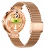 The back of a rose gold smartwatch with a mesh band is shown, highlighting its charging contacts and regulatory information. Podgląd zdjęcia produktu
