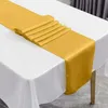 A gold satin table runner is laid out on a white tablecloth. Anteprima dell’immagine prodotto