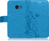 A blue flip case for a smartphone, decorated with embossed floral and butterfly patterns. Produktbild-Vorschau