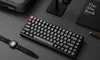 A keyboard and watch are placed on a dark desk next to a book. Produktbild-Vorschau