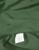 A close-up of a green fabric with a label attached to the elasticated edge. Produktbild-Vorschau