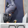 A person is lying on a blue moving blanket, working on a sink. Anteprima dell’immagine prodotto
