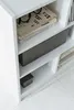A close-up view of a white bookshelf with books and a storage box. Produktbild-Vorschau