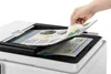 A hand is placing a document into the feeder tray of a white multifunction printer. Produktbild-Vorschau