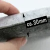 A close-up shot of a hand holding a gray felt cushion, with a measurement overlay indicating approximately 30mm. Produktbild-Vorschau