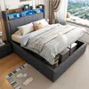 A bedroom scene featuring a modern upholstered bed with storage, illuminated by LED lights in the headboard. The bed is made with blankets and pillows, and the storage compartment underneath is partially open, revealing storage boxes. Anteprima dell’immagine prodotto