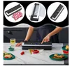 A person is using a vacuum sealer machine on a kitchen counter, with various food items and accessories around. Podgląd zdjęcia produktu