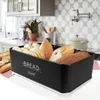 A black bread box filled with various types of bread, placed on a kitchen counter with a tiled backsplash and kitchen cabinets in the background. Produktbild-Vorschau