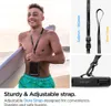 A young man holding a surfboard on a beach, wearing a lanyard with a phone case. Podgląd zdjęcia produktu