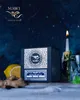 A dark, atmospheric scene with a product box, a lit candle, a glass of liquid, and ingredients for a drink. Voir les images du produit