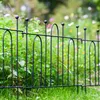 A black metal garden fence is shown in a garden setting with green grass and blurred flowers in the background. Podgląd zdjęcia produktu