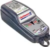 A dark gray battery charger with a white label showing product information and indicators. Voir les images du produit