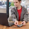 A young woman is using a laptop and a USB hub with an SD card at an outdoor cafe. Produktbild-Vorschau