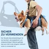 A person is holding a dog in a sling-like carrier, with arrows indicating support. Produktbild-Vorschau