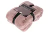 A folded pink faux fur blanket with black straps and a product label. Produktbild-Vorschau