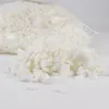 A pile of white, shredded foam material is spilling out of a clear plastic bag onto a white surface. Produktbild-Vorschau