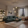 A modern living room with a teal sectional sofa, a coffee table with a candle, a bookshelf, and a large window overlooking a city at night. Produktbild-Vorschau