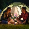 A couple sits in front of a tent at night, with a string of solar-powered flower lights illuminating the scene. Náhled obrázku produktu