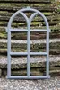 A gray metal window frame with an arched top, set against a stone staircase with moss. Produktbild-Vorschau