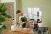 A woman is repotting a plant on a wooden table. Produktbild-Vorschau