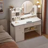 A white vanity table with a mirror and shelves, placed next to a bed. Náhľad obrázku produktu