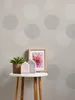 A small round table with decorative items and a plant in front of a patterned wallpaper. Produktbild-Vorschau