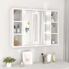 A white mirrored cabinet with LED lights and shelves, mounted on a wall above a desk with some decorative items. Náhľad obrázku produktu