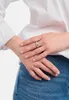 A close-up shot of a person's hands wearing a silver ring, with the person wearing a white shirt and blue jeans. Produktbild-Vorschau