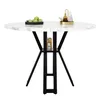 A round dining table with a marble-patterned top and black metal legs, set against a white background. Decorative items are placed on the table. Produktbild-Vorschau