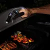 A person is using a grill light to illuminate food on a grill at night. Produktbild-Vorschau