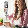 A woman is using a hand blender to make a smoothie. Anteprima dell’immagine prodotto