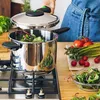 A person is using a pressure cooker on a stove, with fresh vegetables on the side. Anteprima dell’immagine prodotto