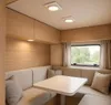 Interior of a camper or RV with a dining area and window. Náhled obrázku produktu