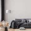 A living room scene with a sofa, floor lamp, and decorative basket. Produktbild-Vorschau