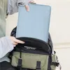 A person is putting a light blue laptop sleeve into a backpack. Produktbild-Vorschau