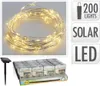 A string of solar-powered LED lights coiled up, with a solar panel stake and a box of packaged lights below. Podgląd zdjęcia produktu