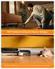 A person is demonstrating a vacuum cleaner's ability to clean under furniture, with a cat nearby. Produktbild-Vorschau