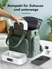 A hand is placing a white ultrasonic cleaner into a green tote bag, with the cleaner and other accessories laid out on a marble surface. Produktbild-Vorschau