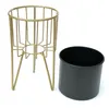 A gold metal plant stand and a black pot are shown against a white background. Podgląd zdjęcia produktu