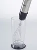 A hand mixer with a whisk attachment is placed inside a clear plastic beaker. Voir les images du produit