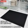 A black doormat is placed on a tiled floor in front of glass doors. Produktbild-Vorschau