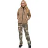 A woman stands facing forward, wearing a tan teddy fleece jacket and camouflage pants. Produktbild-Vorschau