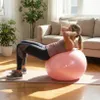 A woman is doing crunches on a pink exercise ball in a living room. Náhled obrázku produktu