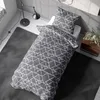A bedroom scene with a bed made with geometric patterned bedding. Produktbild-Vorschau